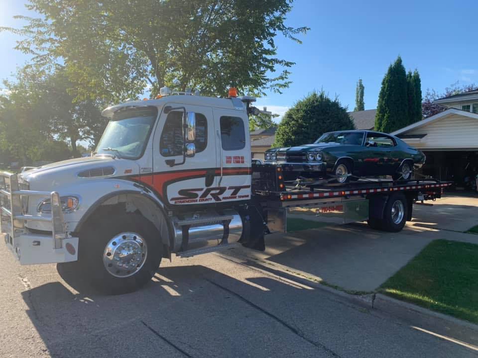 A Flatbed Truck With a Car on the Back