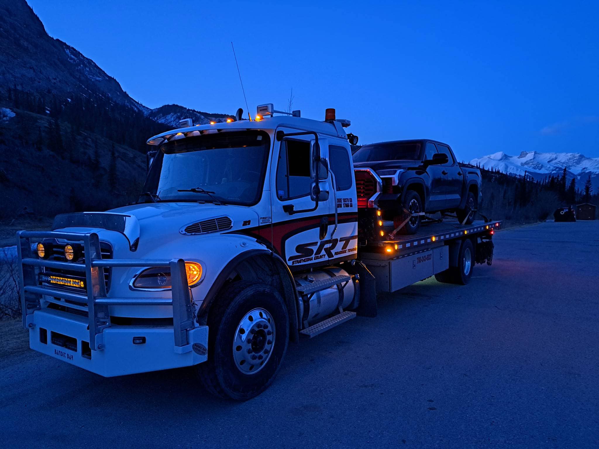 A Flatbed Truck With a Car on the Back