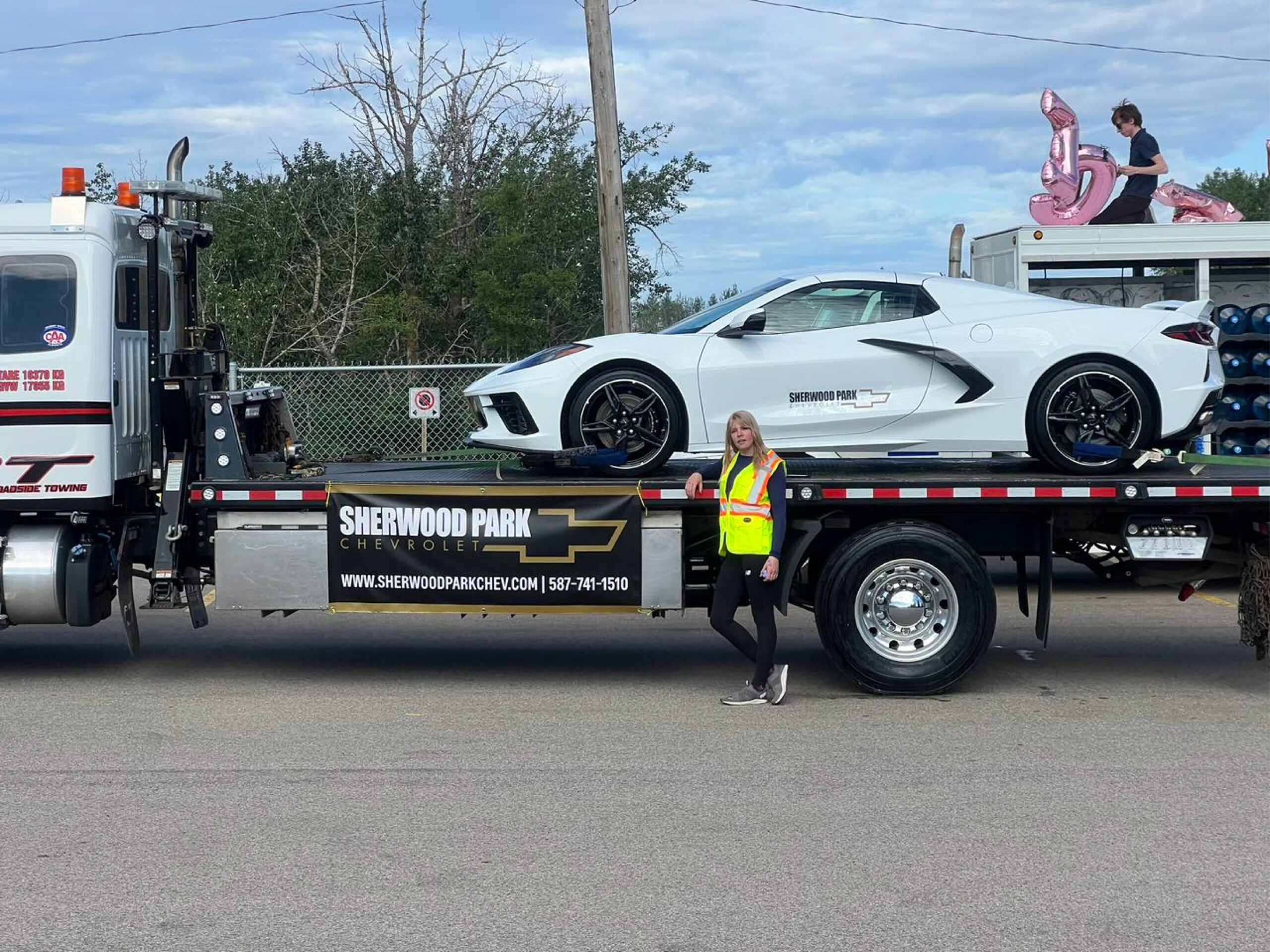 Woman Standing Near to a Truck Carrying a White Sports Car